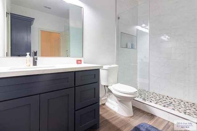 bathroom featuring hardwood / wood-style flooring, vanity, toilet, and a shower with door