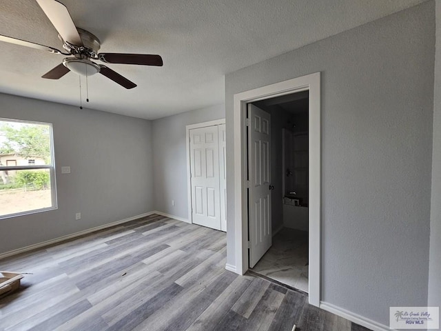 unfurnished bedroom featuring ceiling fan, a closet, a textured ceiling, and light hardwood / wood-style flooring