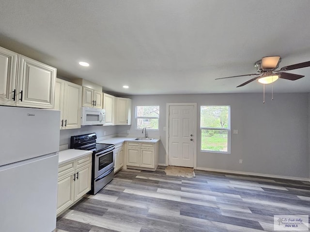 kitchen with white cabinets, light hardwood / wood-style floors, white appliances, and sink