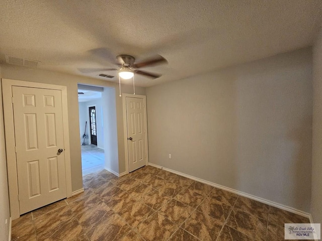 empty room with a textured ceiling and ceiling fan