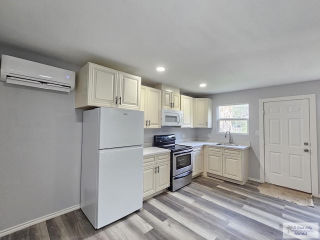 kitchen featuring a wall mounted AC, sink, light hardwood / wood-style floors, and white appliances