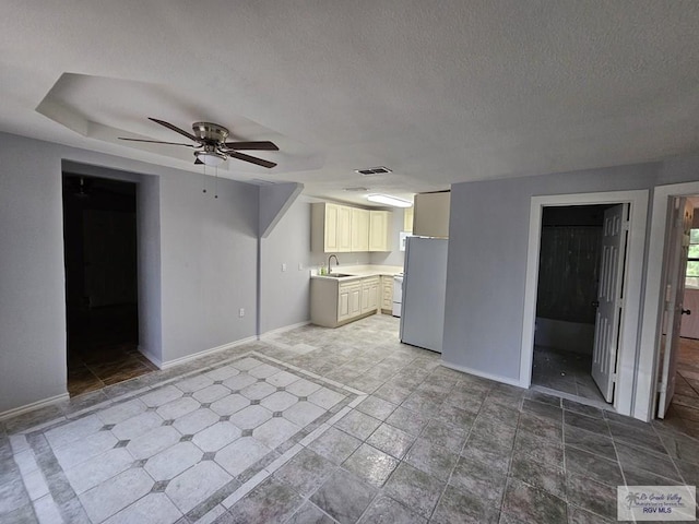 unfurnished living room featuring a textured ceiling, ceiling fan, and sink