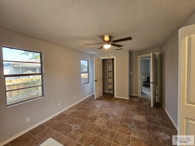 unfurnished bedroom featuring multiple windows, ceiling fan, a closet, and a textured ceiling