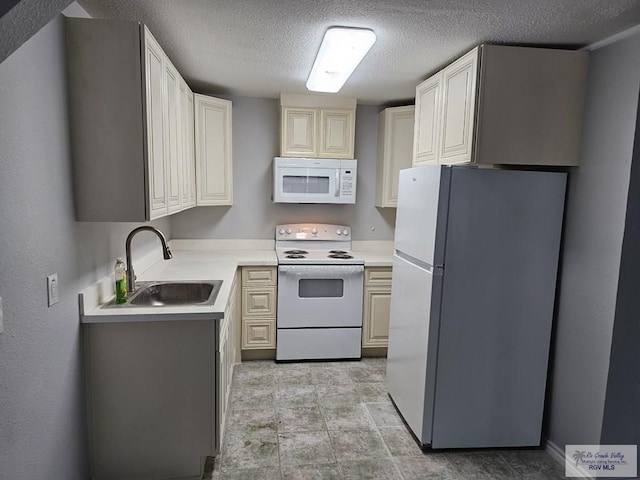 kitchen featuring a textured ceiling, white appliances, and sink