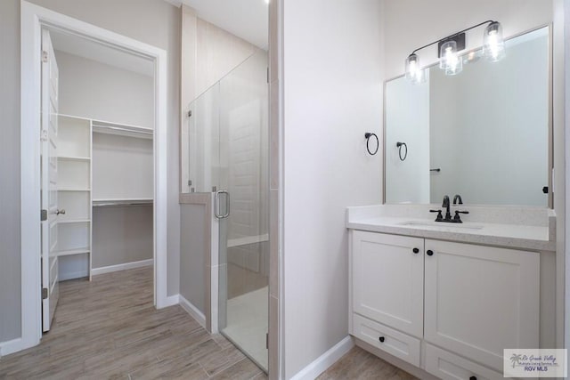3729 Marco Ave, Harlingen, TX 78550 - full bath with a stall shower, wood finished floors, vanity, a walk in closet, and baseboards