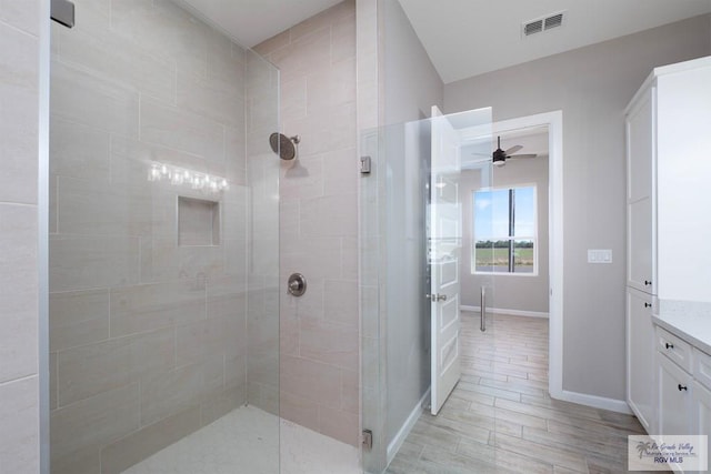 bathroom featuring hardwood / wood-style floors, ceiling fan, walk in shower, and vanity