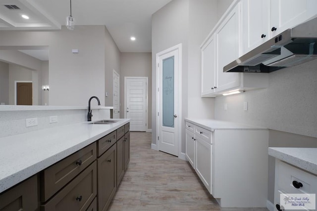 kitchen with white cabinetry, sink, pendant lighting, light hardwood / wood-style floors, and dark brown cabinets