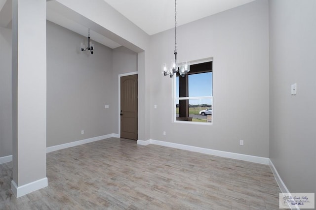 unfurnished room with light hardwood / wood-style flooring and a chandelier