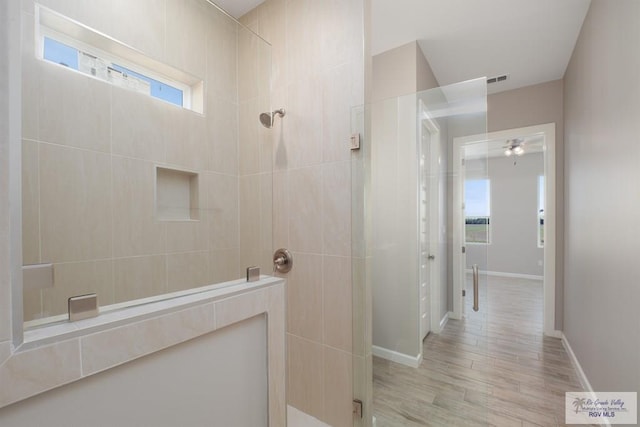 bathroom with hardwood / wood-style floors and tiled shower