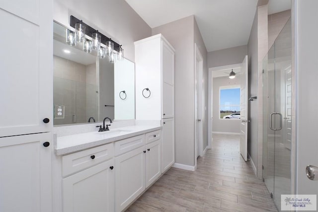 bathroom featuring hardwood / wood-style flooring, vanity, ceiling fan, and a shower with door