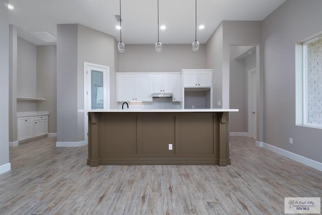 kitchen featuring pendant lighting, a spacious island, white cabinetry, and light hardwood / wood-style flooring