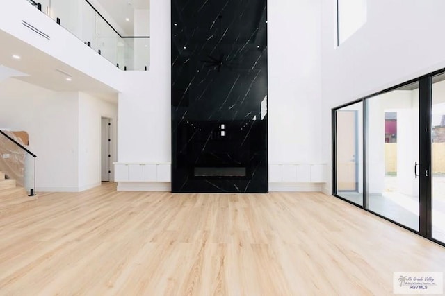 unfurnished living room featuring stairs, a high ceiling, and wood finished floors