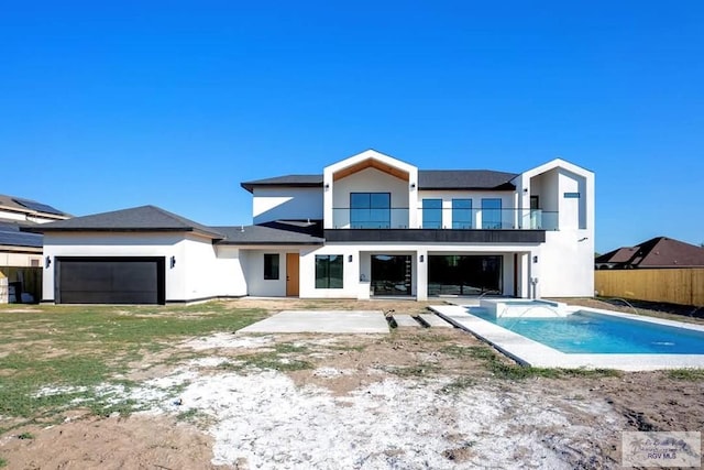 rear view of property featuring an attached garage, a patio area, a balcony, and stucco siding