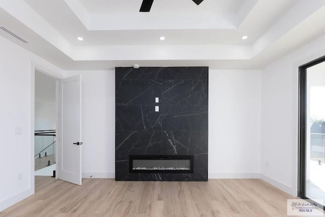 details featuring a fireplace, baseboards, a raised ceiling, and wood finished floors