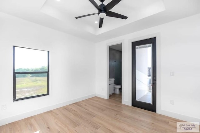 spare room with recessed lighting, a raised ceiling, light wood-style floors, ceiling fan, and baseboards