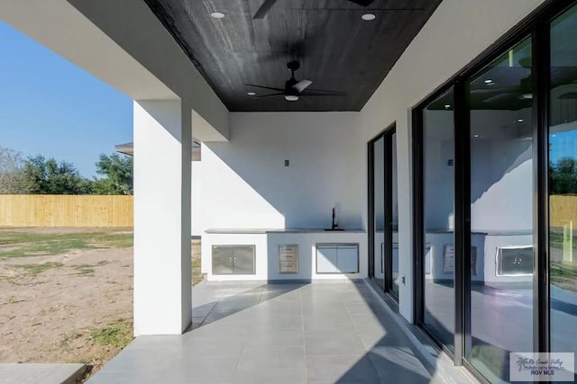 view of patio / terrace featuring ceiling fan, exterior kitchen, and fence