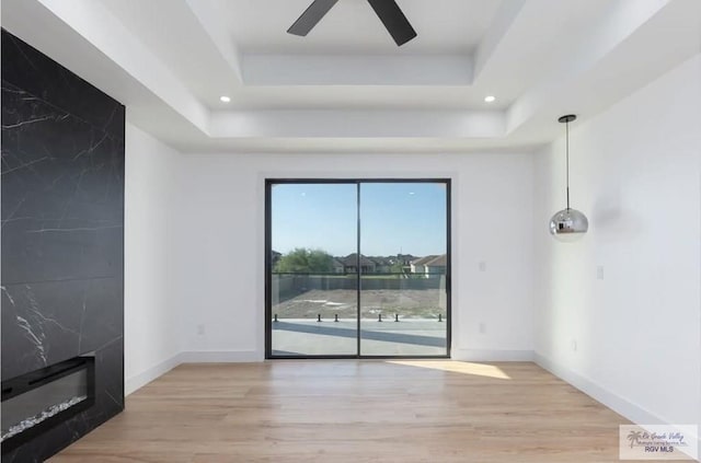 interior space featuring wood finished floors, a raised ceiling, and baseboards