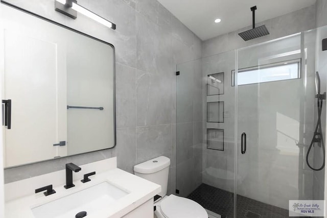 bathroom featuring a stall shower, tile walls, toilet, and vanity