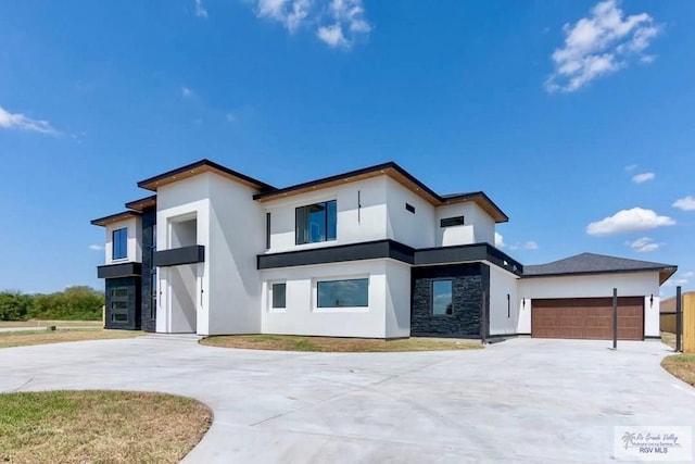 modern home featuring a garage, driveway, stone siding, and stucco siding