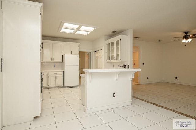 212 E Xenops Ave, Mcallen, TX 78504 - kitchen with freestanding refrigerator, a kitchen breakfast bar, glass insert cabinets, light tile patterned flooring, and light countertops