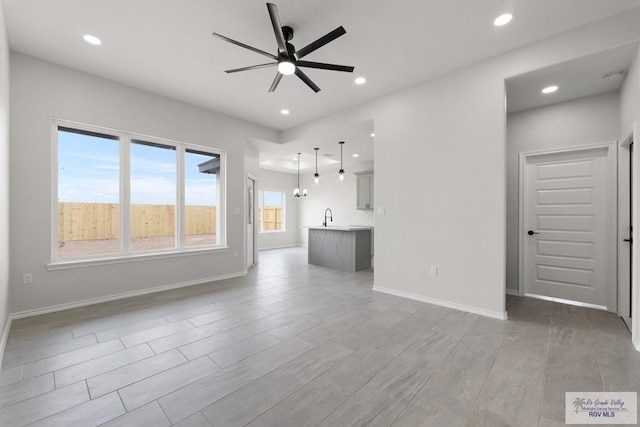 unfurnished living room featuring ceiling fan, sink, and light wood-type flooring