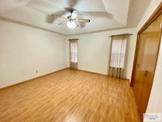 interior space with ceiling fan, a raised ceiling, a closet, and light hardwood / wood-style flooring