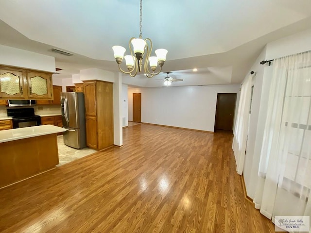 kitchen featuring pendant lighting, ceiling fan with notable chandelier, stainless steel appliances, and light wood-type flooring