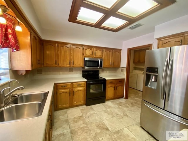 kitchen featuring appliances with stainless steel finishes, washer and clothes dryer, sink, and backsplash