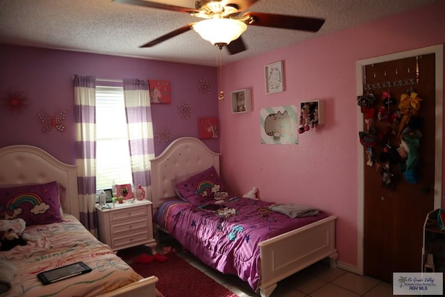 bedroom with ceiling fan, light tile patterned floors, and a textured ceiling