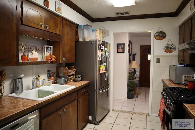 kitchen featuring a textured ceiling, ornamental molding, sink, and appliances with stainless steel finishes