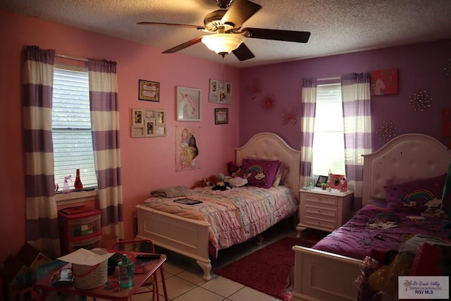 bedroom featuring ceiling fan, a textured ceiling, and multiple windows