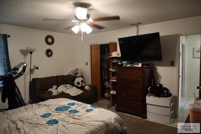 tiled bedroom featuring ceiling fan, a closet, and a textured ceiling