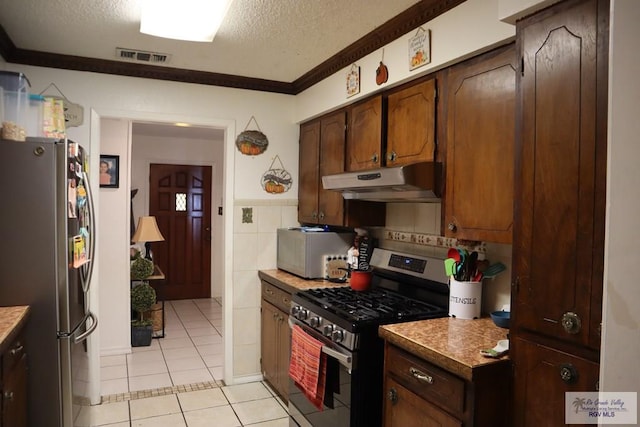 kitchen with light tile patterned floors, a textured ceiling, stainless steel appliances, and ornamental molding