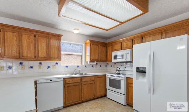 kitchen featuring backsplash, white appliances, sink, and a textured ceiling