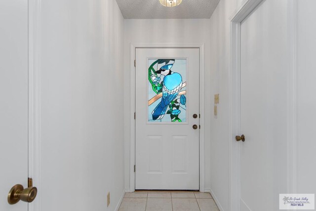 doorway to outside with light tile patterned floors and a textured ceiling