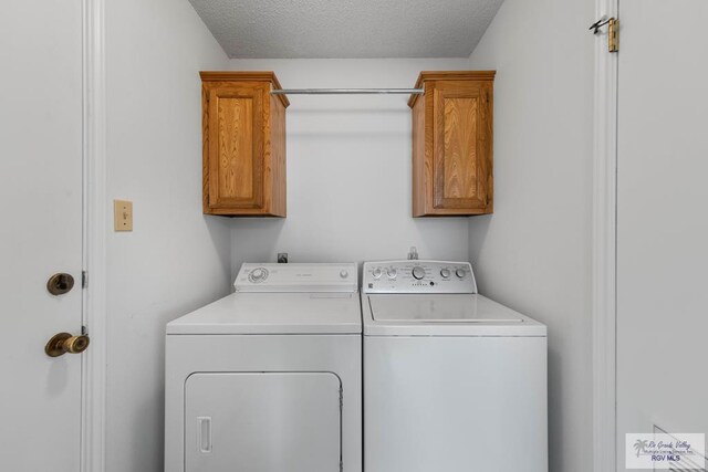 clothes washing area featuring cabinets, a textured ceiling, and washing machine and clothes dryer