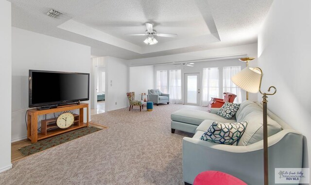 carpeted living room with a raised ceiling, ceiling fan, french doors, and a textured ceiling