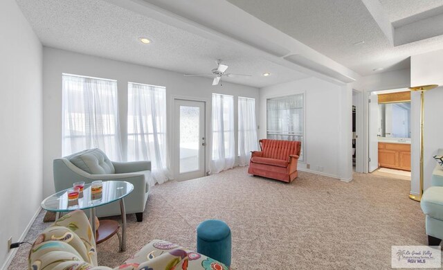 carpeted living room with a textured ceiling and ceiling fan