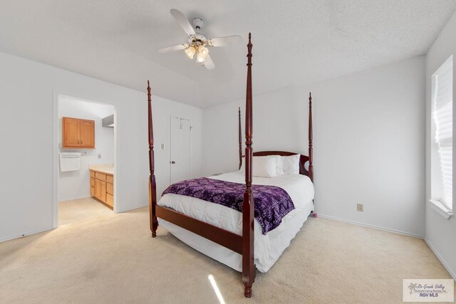 carpeted bedroom with ceiling fan, ensuite bathroom, and a textured ceiling