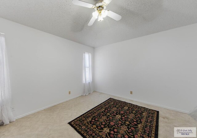 unfurnished room with ceiling fan, light colored carpet, and a textured ceiling