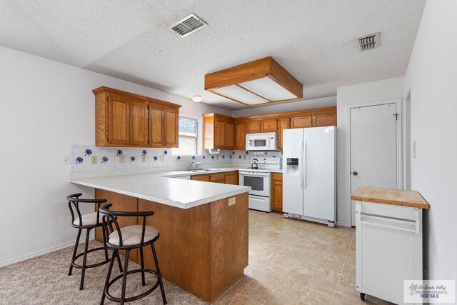 kitchen with white appliances, backsplash, sink, a textured ceiling, and kitchen peninsula