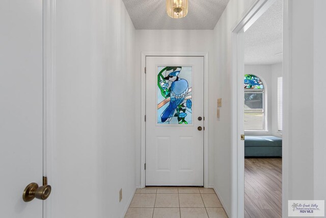 doorway featuring a textured ceiling and light hardwood / wood-style flooring