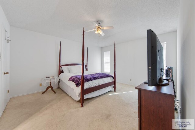 carpeted bedroom featuring ceiling fan and a textured ceiling