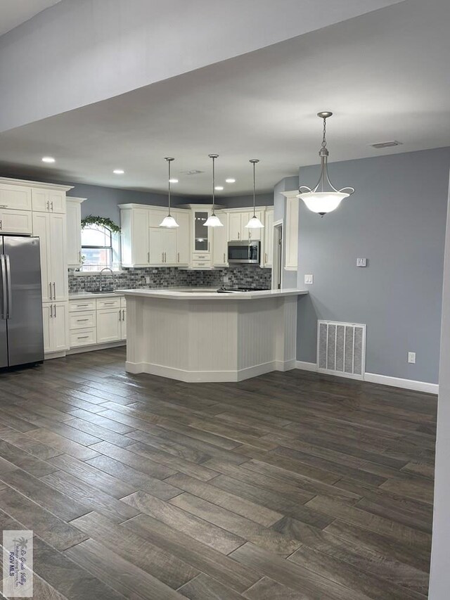 kitchen featuring sink, hanging light fixtures, stainless steel appliances, dark hardwood / wood-style flooring, and white cabinets