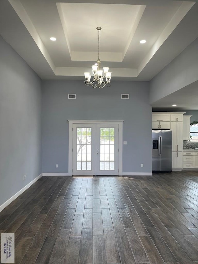 interior space with dark hardwood / wood-style floors, french doors, a chandelier, and a tray ceiling