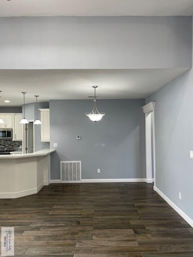 kitchen featuring white cabinets, dark hardwood / wood-style flooring, stainless steel appliances, and hanging light fixtures