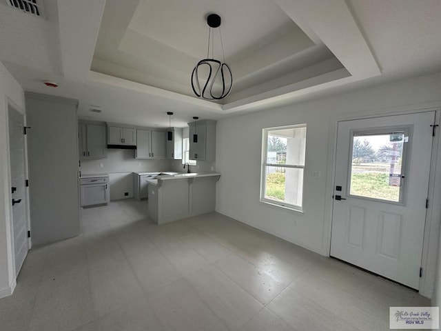 kitchen featuring gray cabinetry, a raised ceiling, sink, an inviting chandelier, and hanging light fixtures