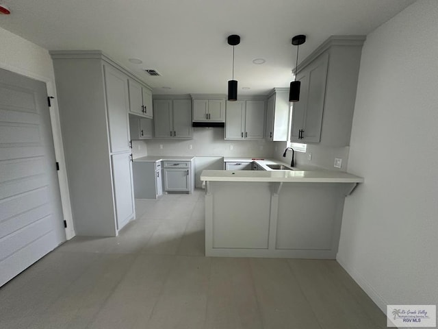 kitchen with kitchen peninsula, gray cabinets, hanging light fixtures, and sink