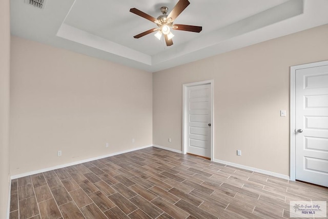 9725 Hawk Dr, Harlingen, TX 78552 - unfurnished room featuring a tray ceiling, a ceiling fan, baseboards, and wood finished floors