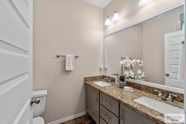 9725 Hawk Dr, Harlingen, TX 78552 - bathroom featuring toilet, double vanity, baseboards, and wood finished floors